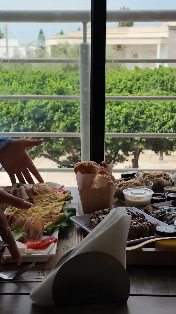 Une table de brunch à partager devant la baie vitrée : croissants en cornet, omelette, crêpes au chocolat et petits pots.