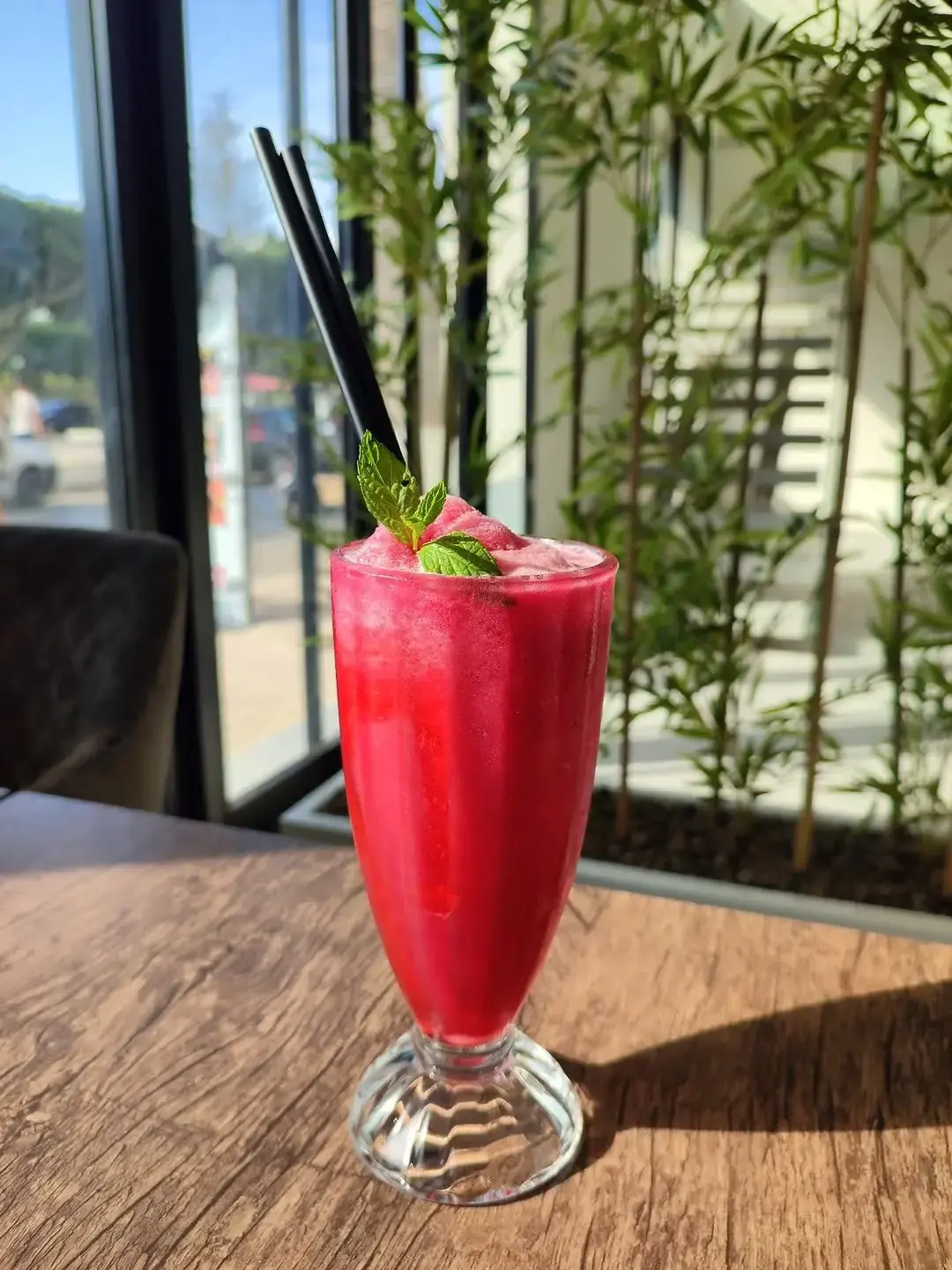 Cocktail de fruits rouges à la menthe, posé devant la baie vitrée.