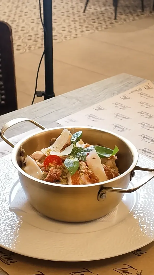 Une petite cocotte en inox garnie, relevée de tomate cerise, de basilic frais et de copeaux de parmesan.