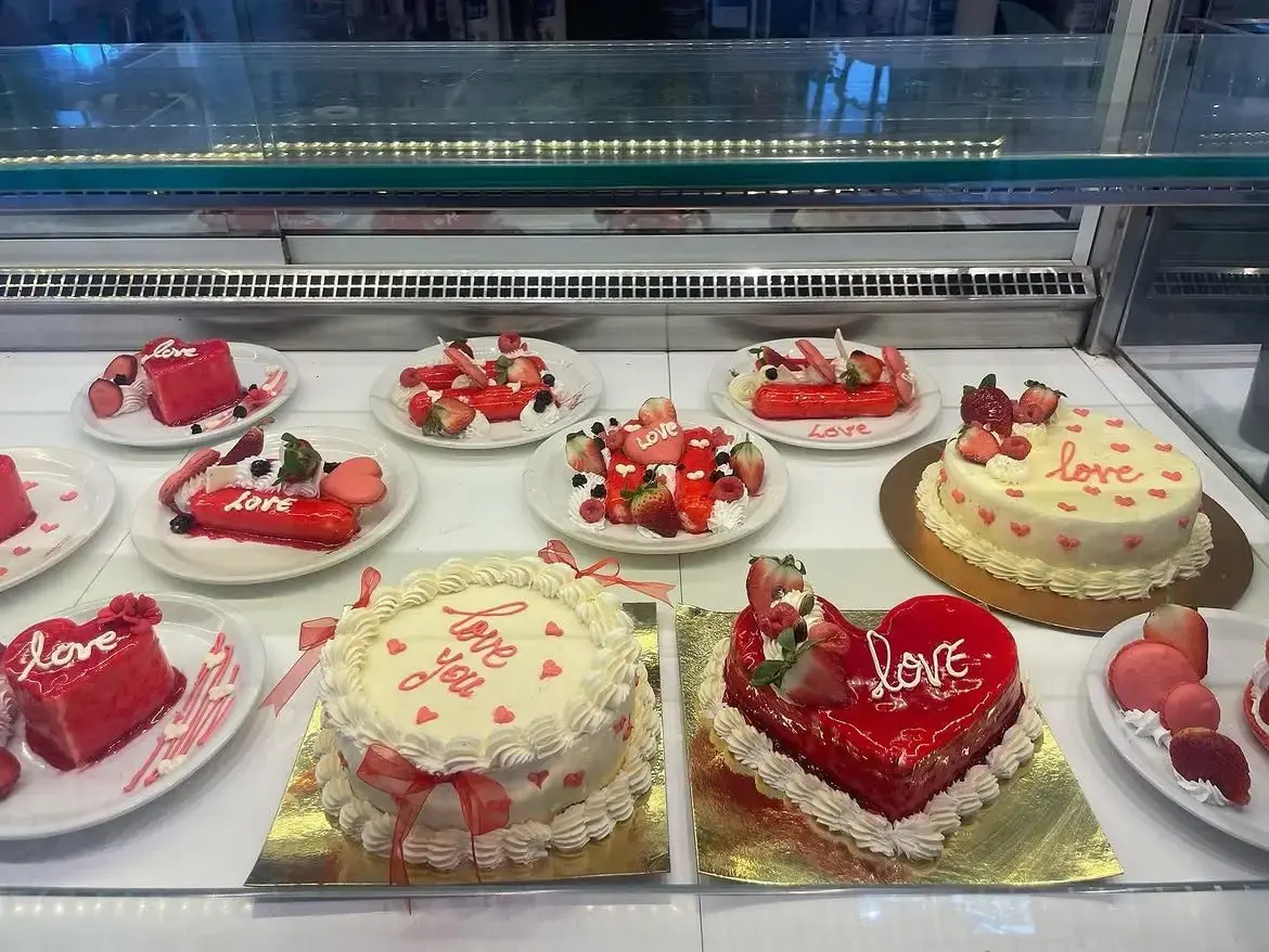 Vitrine réfrigérée garnie de gâteaux et d'entremets décorés de cœurs et de fraises.