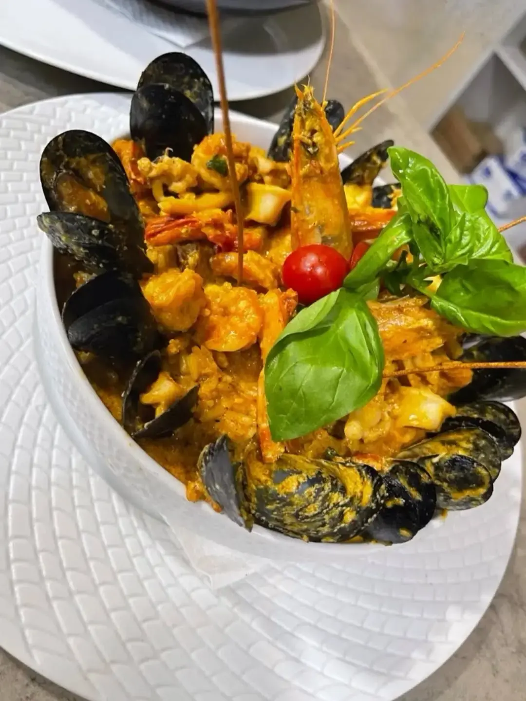 Plat de fruits de mer aux moules, gambas et calamars, relevé de basilic frais.