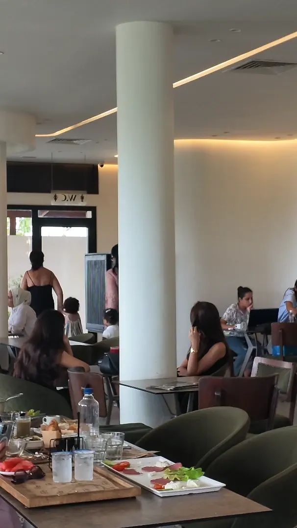 La salle du Twins pleine : colonnes blanches, bandeaux lumineux au plafond et tables garnies.